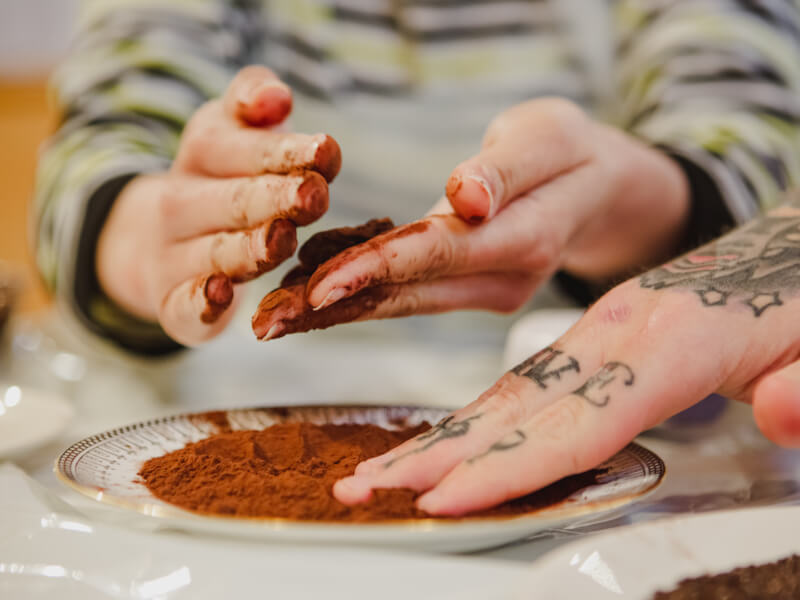 Hands in chocolate powder at cake decorating class.